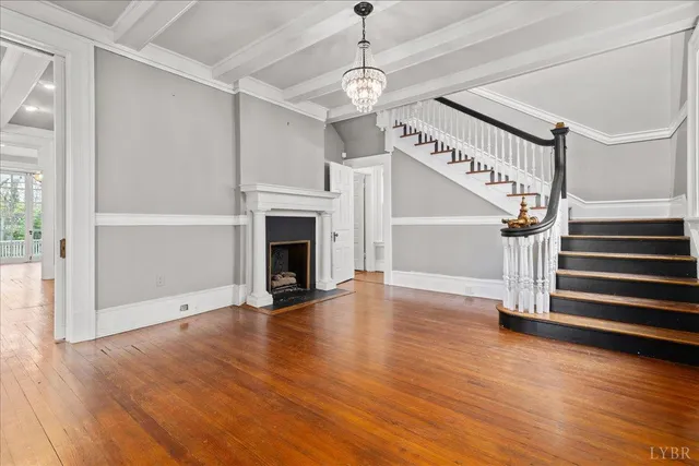 a view of a livingroom with wooden floor staircase and a fireplace