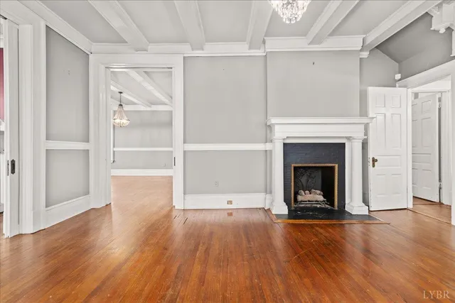 a view of an empty room with wooden floor fireplace and a window