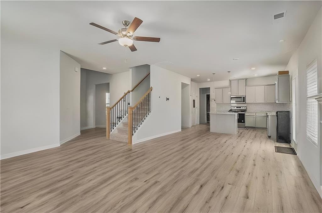 1101 Longleaf Trace Monroe, GA 30656 - Photo 12 of 36 a view of an empty room with wooden floor and a ceiling fan