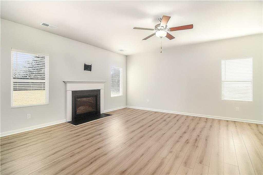 1101 Longleaf Trace Monroe, GA 30656 - Photo 9 of 36 an empty room with wooden floor a fireplace and windows