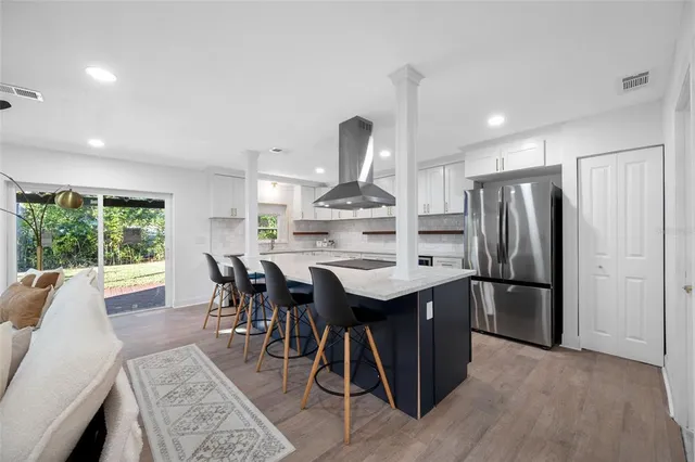 a kitchen with kitchen island a dining table chairs stainless steel appliances and cabinets