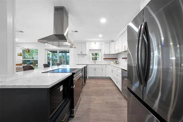 an open kitchen with kitchen island a large counter top space a sink stainless steel appliances and cabinets