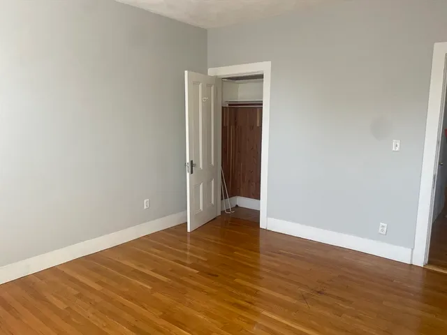 a view of an empty room with wooden floor and closet