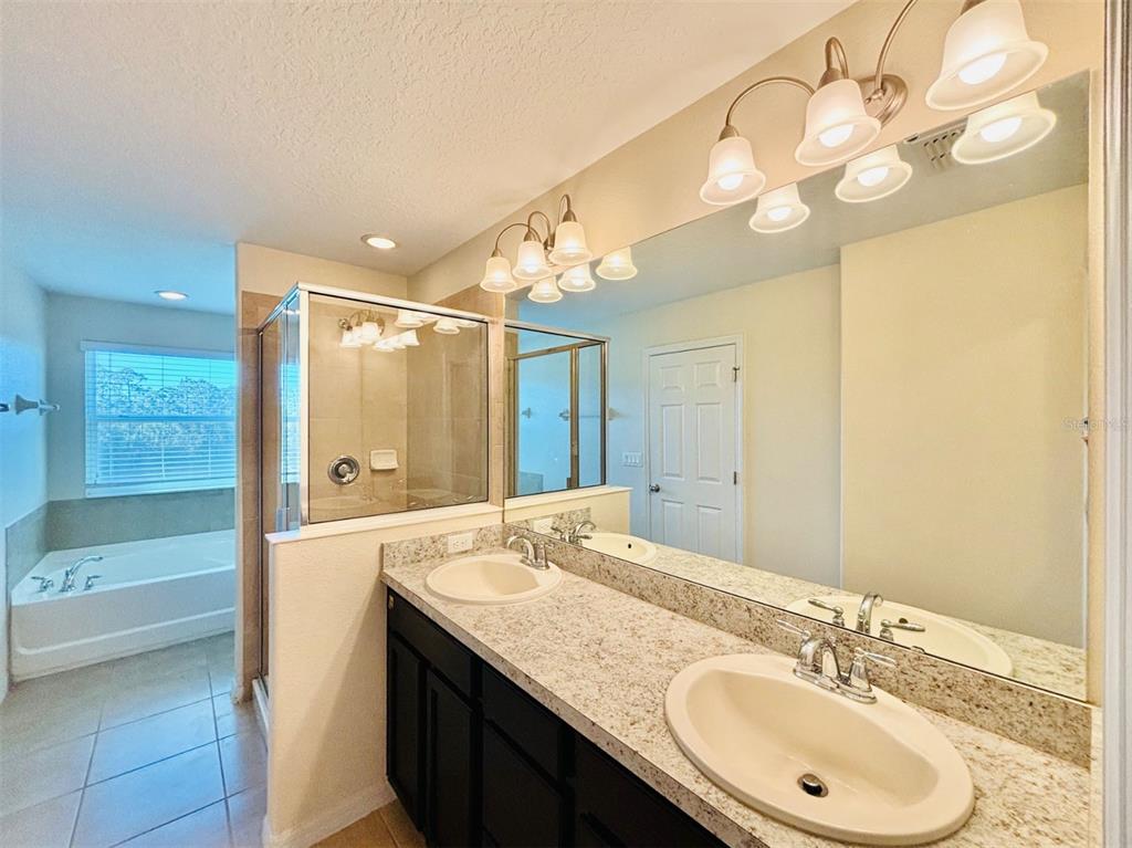 2144 Rookery Lane Sanford, FL 32773 - Photo 26 of 41 a bathroom with a granite countertop sink a large mirror and a bathtub