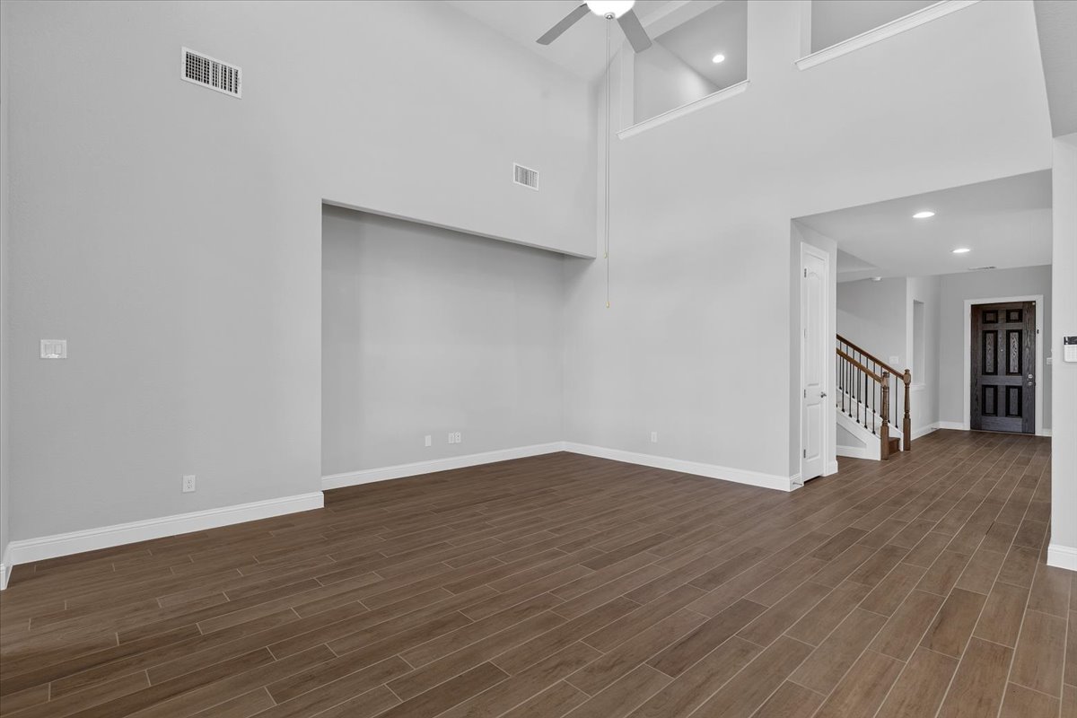 109 Rocky River Road Georgetown, TX 78628 - Photo 8 of 37 A spacious living area features high ceilings and wood-look tile flooring, leading to an elegant staircase.