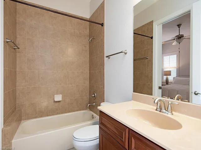 a bathroom with a granite countertop bathtub shower sink vanity and toilet
