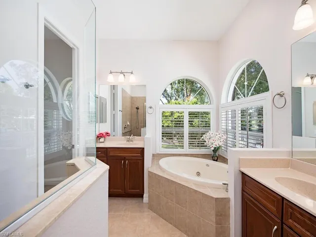 a bathroom with a granite countertop tub a sink and a large window