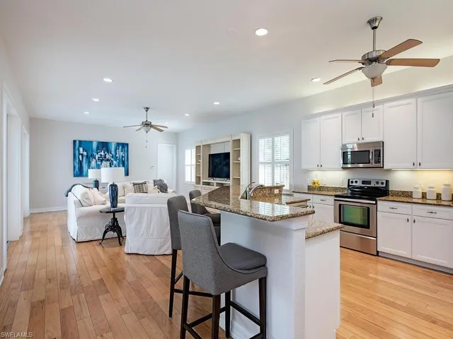 a living room with stainless steel appliances kitchen island granite countertop furniture wooden floor and a view of kitchen