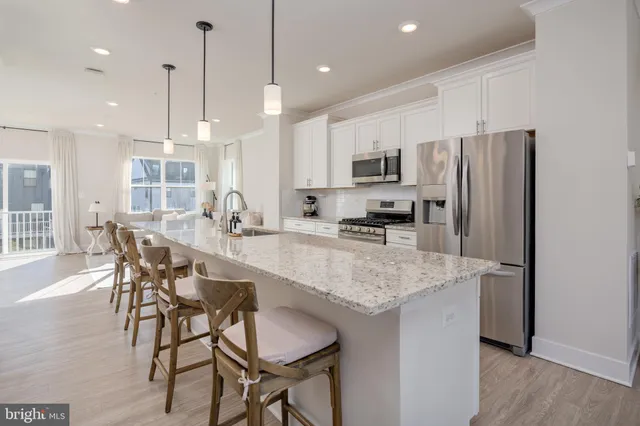 a kitchen with kitchen island granite countertop a table chairs microwave and white cabinets