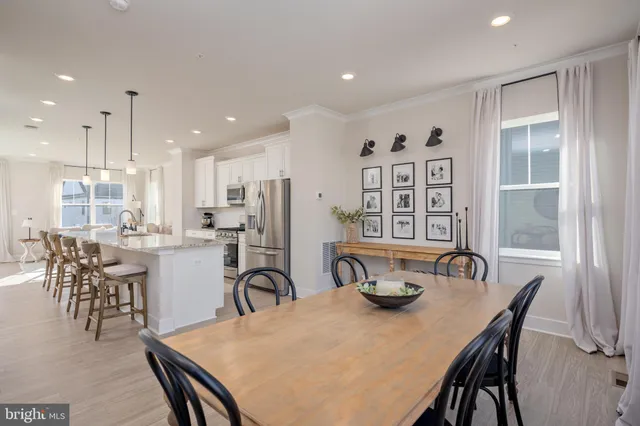 a kitchen with a dining table chairs and refrigerator
