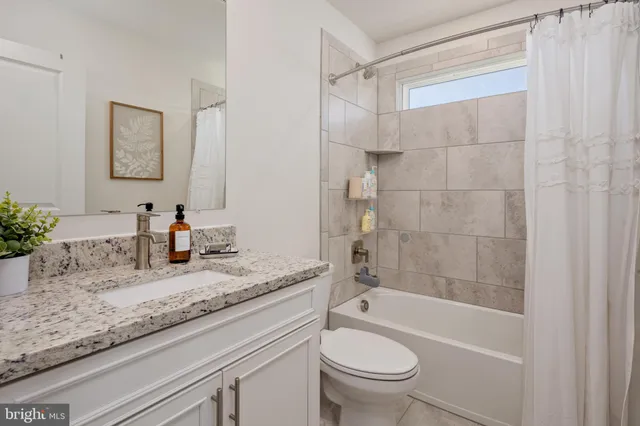a bathroom with a granite countertop sink a toilet and bathtub
