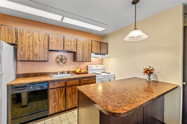 a kitchen with stainless steel appliances granite countertop a sink a stove and a wooden cabinets
