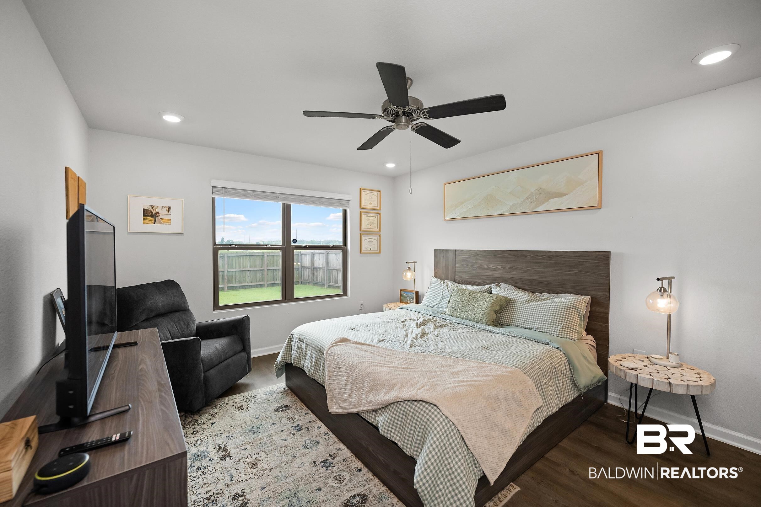 32030 Terranova Loop Lillian, AL 36549 - Photo 10 of 30 Spacious bedroom featuring wood-finish flooring, a contemporary ceiling fan, recessed lighting, a large window overlooking a fenced yard, and a built-in dark wood headboard