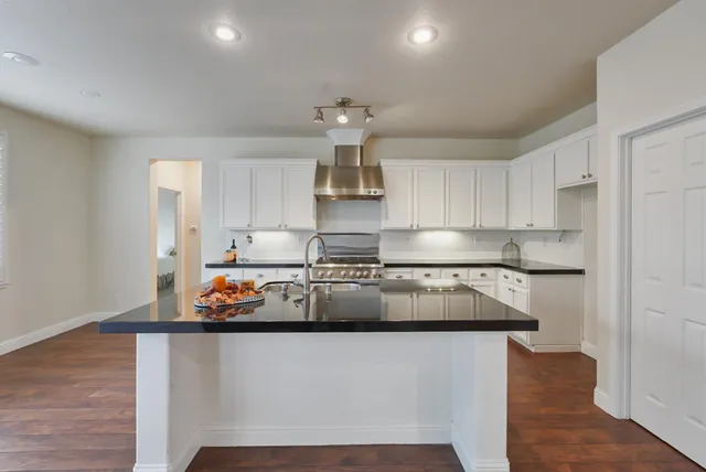 a kitchen with stainless steel appliances a stove a sink and white cabinets