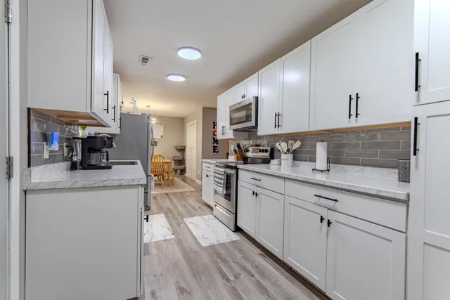 a kitchen with stainless steel appliances granite countertop a sink a stove and cabinets
