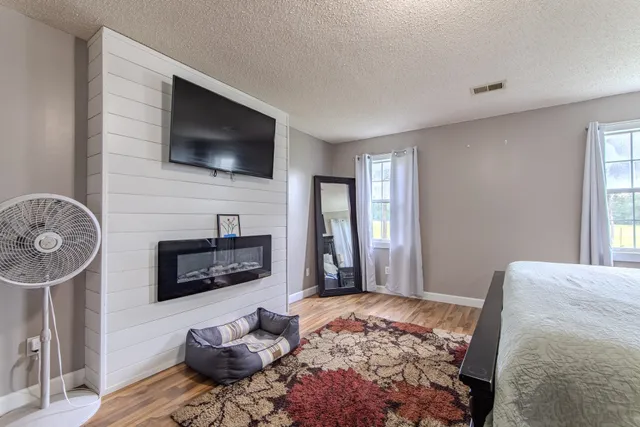 a bedroom with a bed a mirror and a flat tv screen on dresser