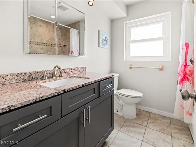 a bathroom with a granite countertop sink a toilet and a mirror