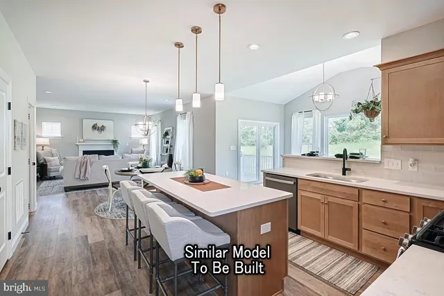 a open kitchen with stainless steel appliances granite countertop a sink a stove a dining table and chairs with wooden floor