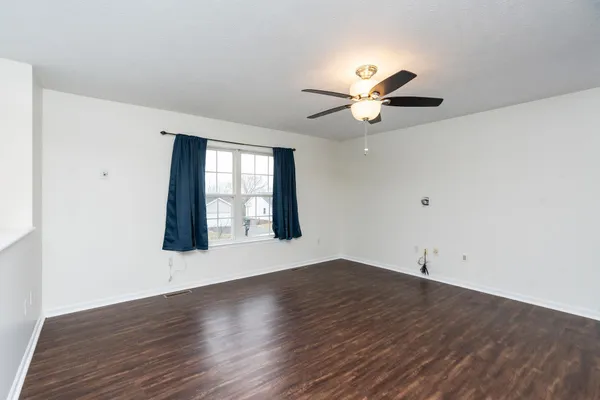 a view of an empty room with window and wooden floor