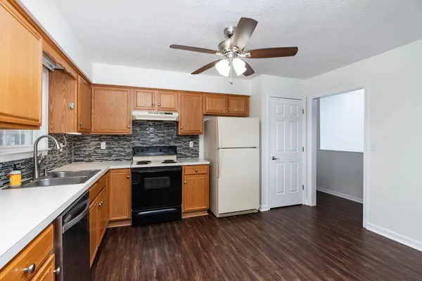 a kitchen with stainless steel appliances granite countertop a refrigerator a sink dishwasher a stove and white countertops with wooden floor
