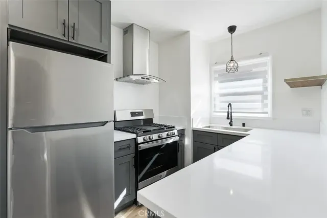 a kitchen with stainless steel appliances a refrigerator a stove and white cabinets
