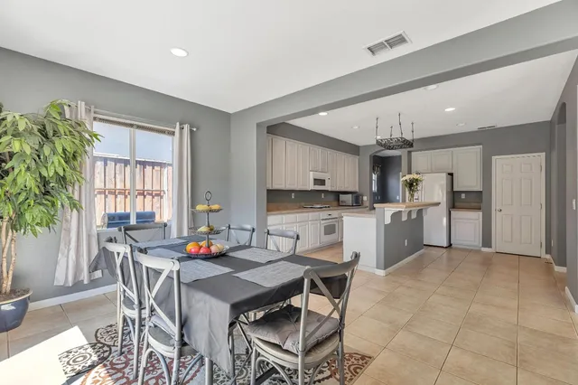 a open dining room with stainless steel appliances a table and chairs