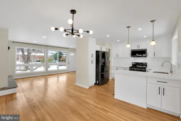 a kitchen with stainless steel appliances kitchen island granite countertop a refrigerator a stove a microwave oven a large island with wooden floor and cabinets