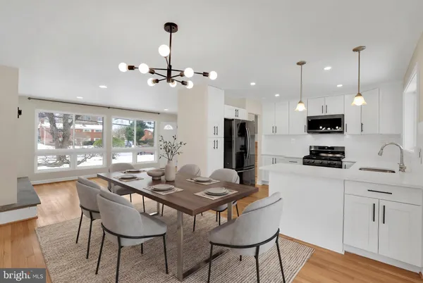 a kitchen with stainless steel appliances kitchen island granite countertop a dining table chairs and white cabinets