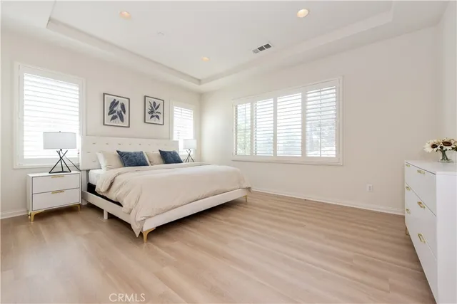 a bedroom with a white bed and white walls with wooden floor