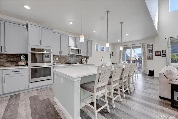 a kitchen with stainless steel appliances kitchen island granite countertop a table chairs sink and cabinets