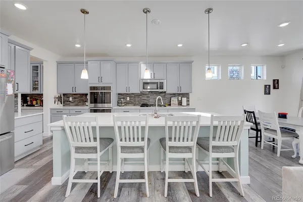 a kitchen with kitchen island granite countertop a dining table chairs and white cabinets