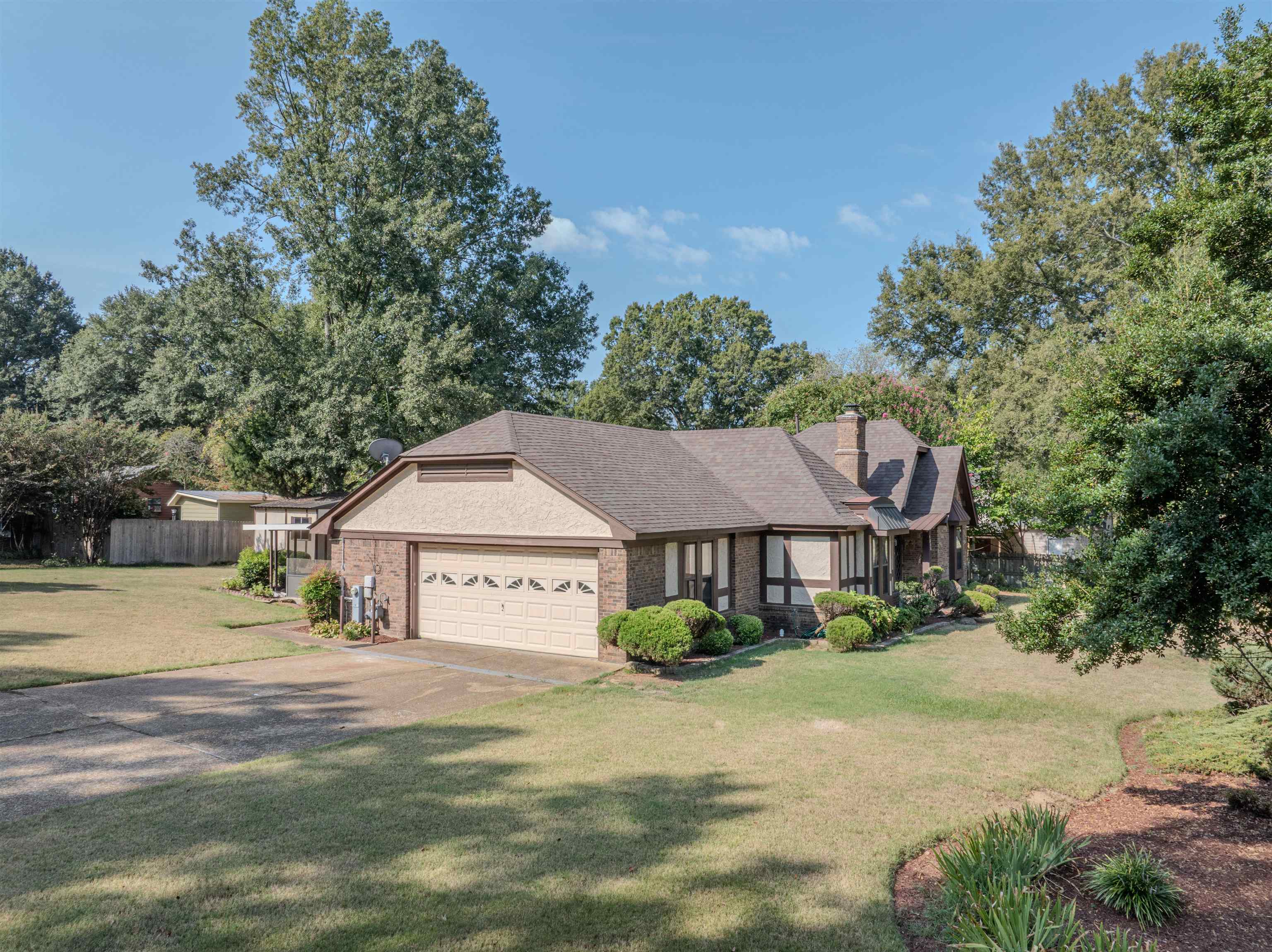 125 East Harpers Ferry Road Collierville, TN 38017 - Photo 3 of 40 View of front of home featuring a chimney, driveway, brick siding, a garage, and view of wooded area