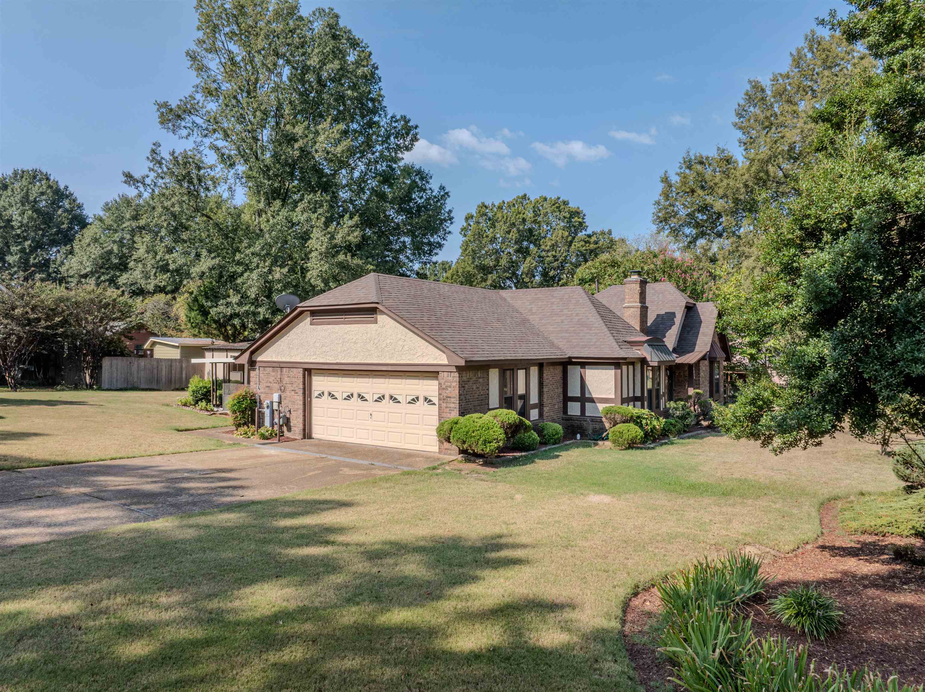 125 East Harpers Ferry Road Collierville, TN 38017 - Photo 8 of 40 View of front of property with brick siding, driveway, an attached garage, a chimney, and view of wooded area