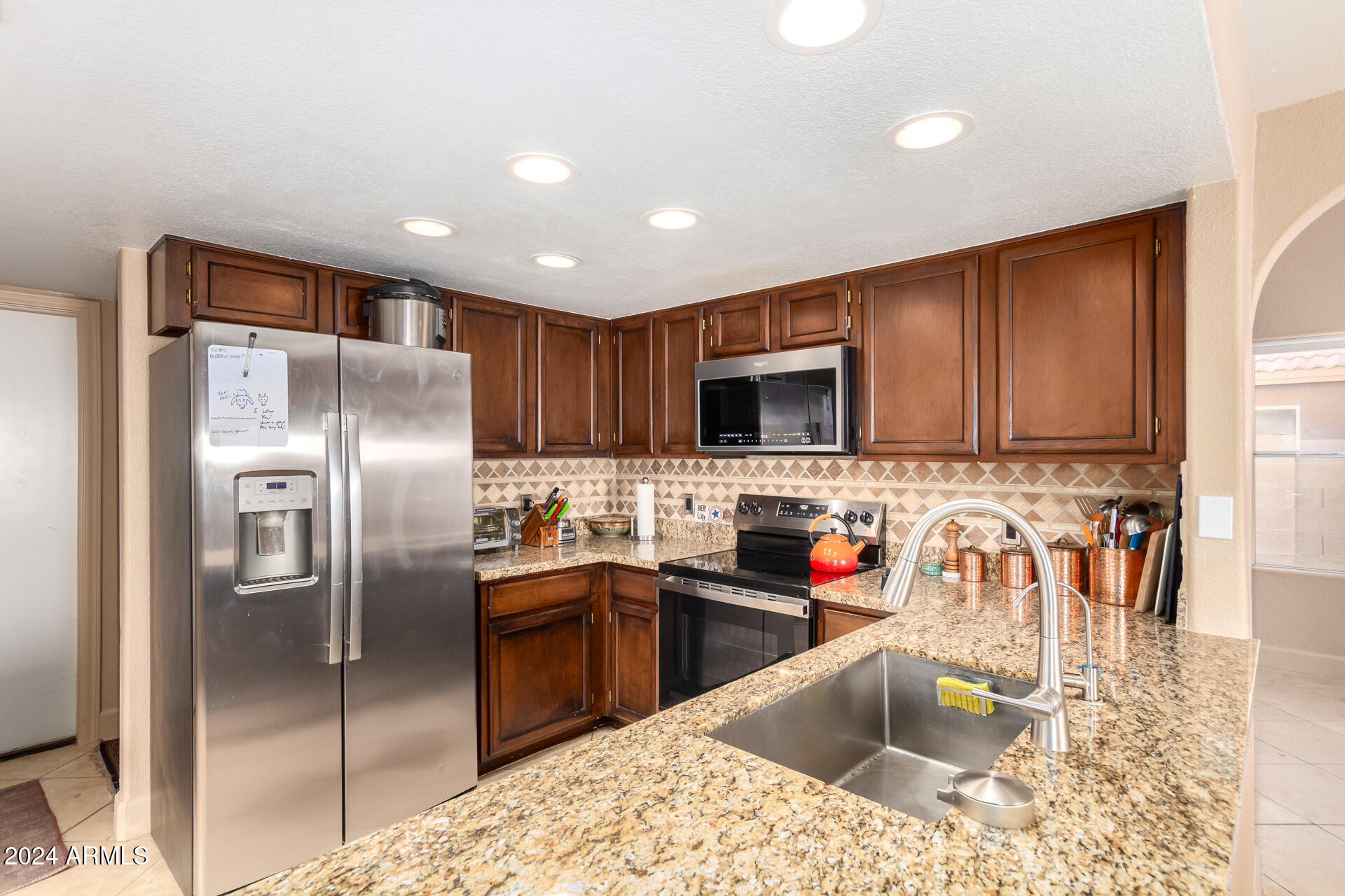 1836 North Stapley Drive, Unit 102 Mesa, AZ 85203 - Photo 13 of 34 a kitchen with stainless steel appliances kitchen island granite countertop a sink refrigerator and microwave