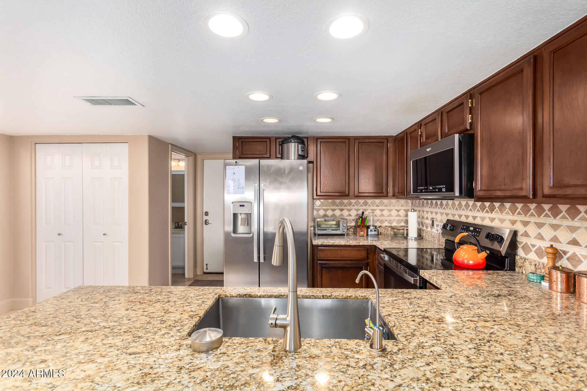 1836 North Stapley Drive, Unit 102 Mesa, AZ 85203 - Photo 16 of 34 a kitchen with stainless steel appliances granite countertop a sink refrigerator and microwave