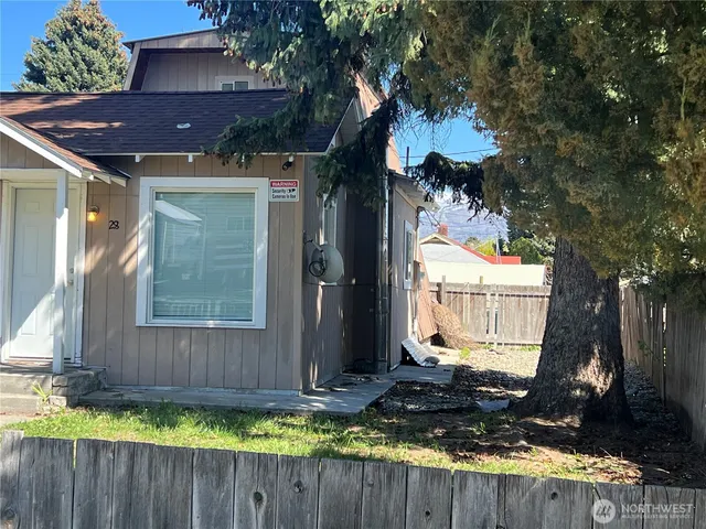 a view of house with yard outdoor seating and trees in the background