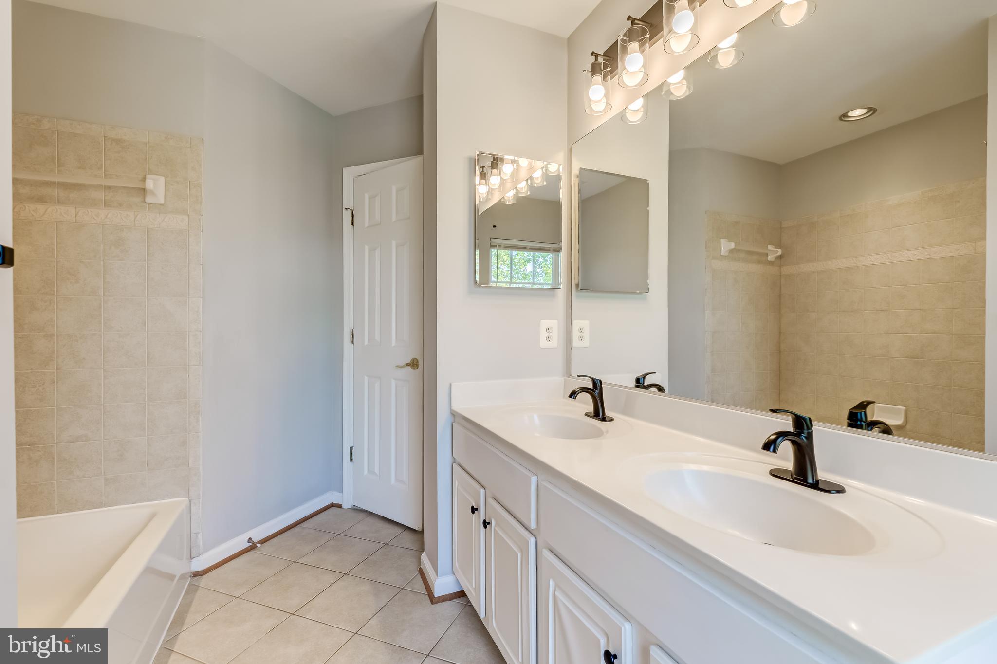 19111 Chartier Drive Leesburg, VA 20176 - Photo 32 of 68 a bathroom with a double vanity sink and a mirror