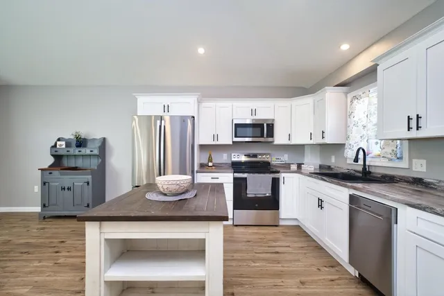 a kitchen with kitchen island granite countertop a stove sink and microwave