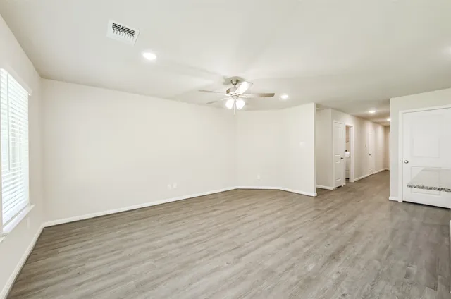 an empty room with a window and a ceiling fan