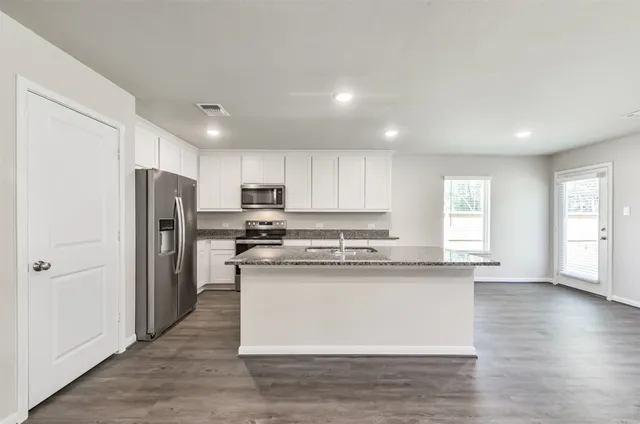 a kitchen with stainless steel appliances granite countertop a refrigerator a sink dishwasher a stove and white countertops with wooden floor