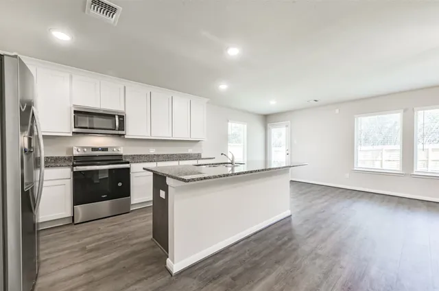 a kitchen with stainless steel appliances granite countertop a stove a sink and a refrigerator