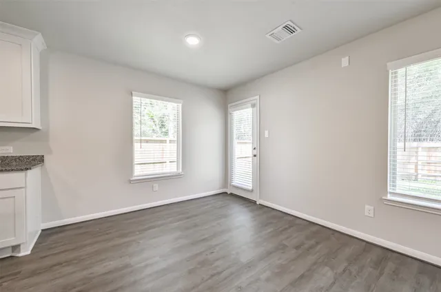 an empty room with wooden floor and windows