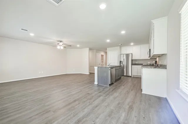 a view of an empty room with window and wooden floor