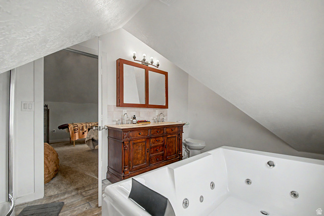 12645 East Cedar Ridge Drive Fairview, UT 84629 - Photo 16 of 34 White jetted tub with multiple jets, accompanied by a double vanity featuring an ornate wood-finish cabinet, marble-look countertop, and dual mirrors