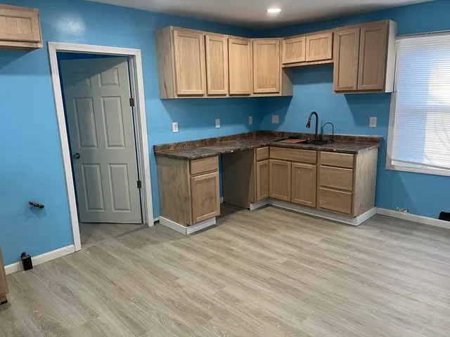 a kitchen with granite countertop a sink cabinets and wooden floor
