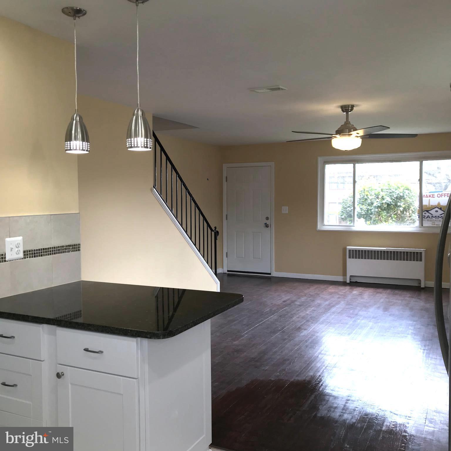 7900 Riggs Road Hyattsville, MD 20783 - Photo 6 of 9 a kitchen with kitchen island a sink dishwasher a stove and a dining table with wooden floor