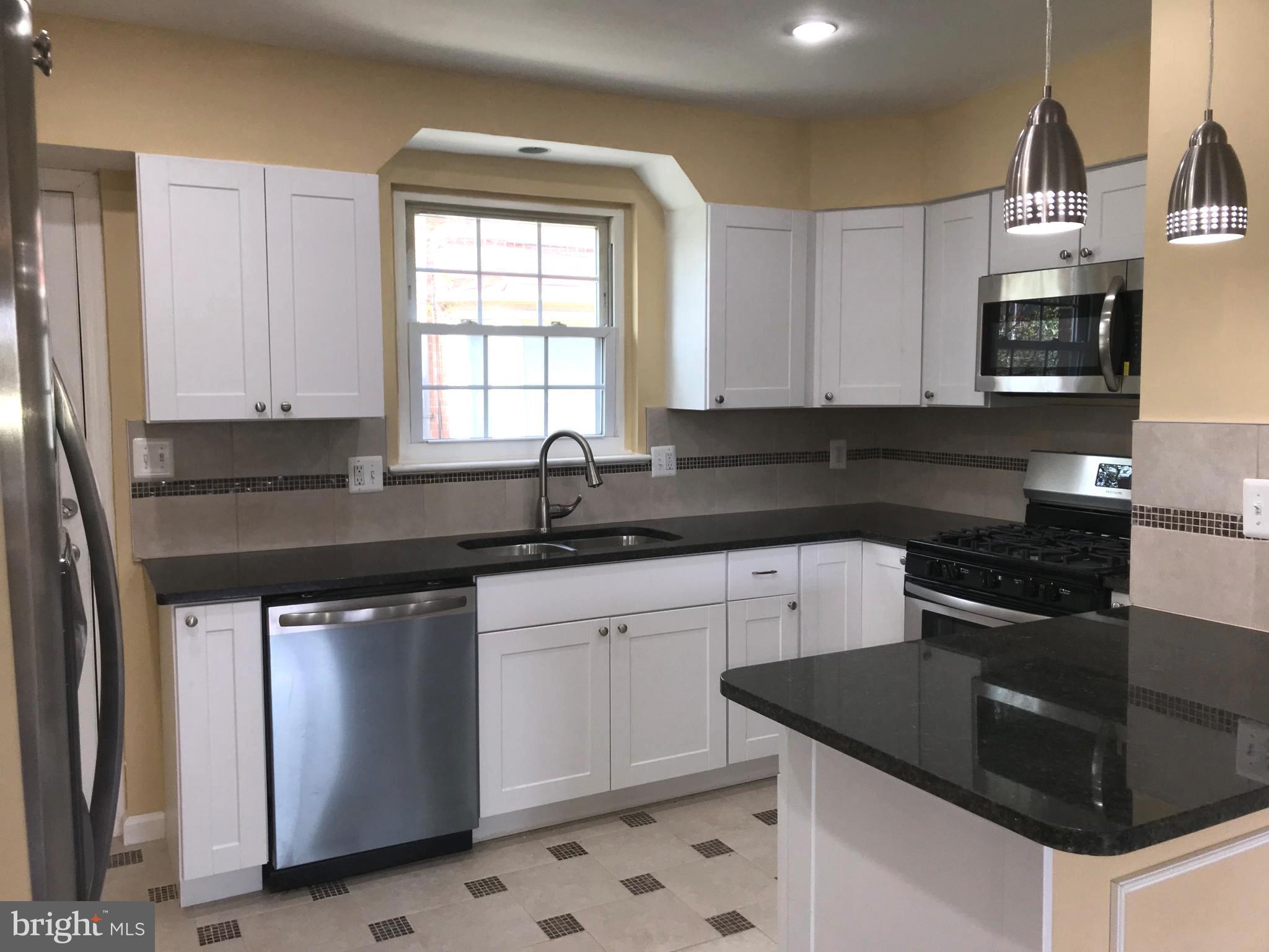 7900 Riggs Road Hyattsville, MD 20783 - Photo 7 of 9 a kitchen with granite countertop a sink a stove and cabinets