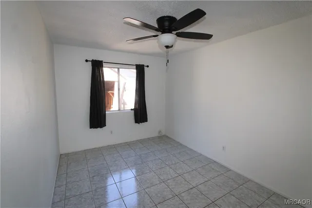 an empty room with windows and fan