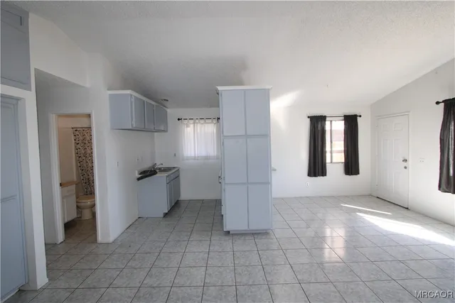 a view of a kitchen with refrigerator and white walls
