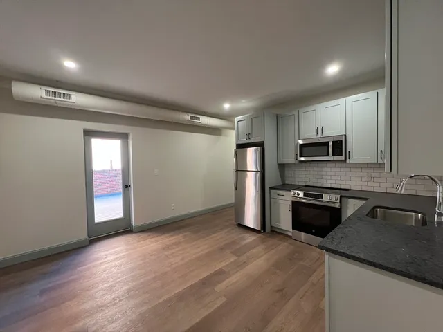 a kitchen with granite countertop a refrigerator and a stove top oven